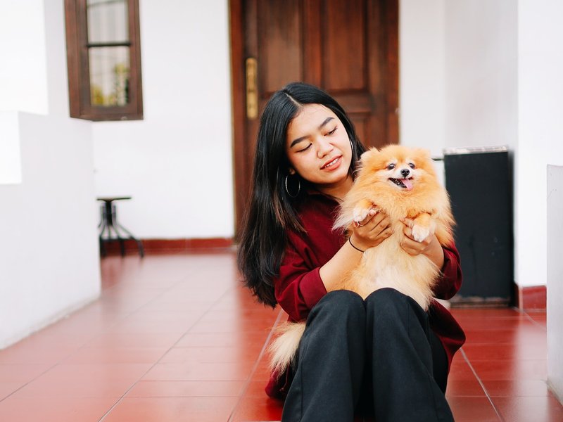 Girl and small dog sitting on red tile flooring